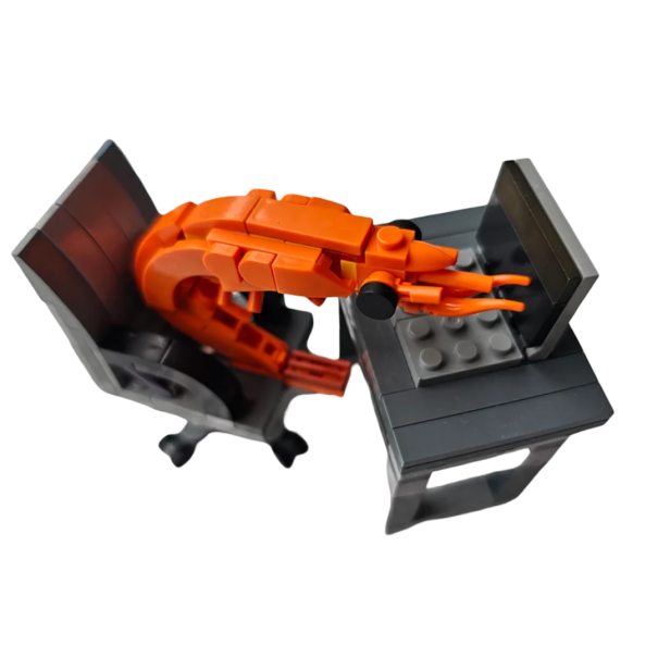 Costruzione per bambini a forma di gambero, seduto in ufficio a una scrivania con un laptop su una sedia girevole, originale puzzle da ufficio 1