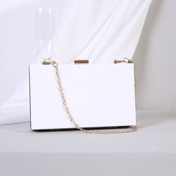 Dámska kabelka psaníčko vo forme krabičky Pevné plastové telo Zlatá spona a reťazkový popruh Čisté pravoúhlé línie 17 x 10 x 4 cm biela