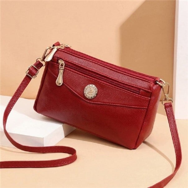 Dámská malá crossbody kabelka s kulatou kovovou ozdobou Přední kapsa na zip Nastavitelný popruh PU kůže a polyester 22 x 15 x 8 cm vínová