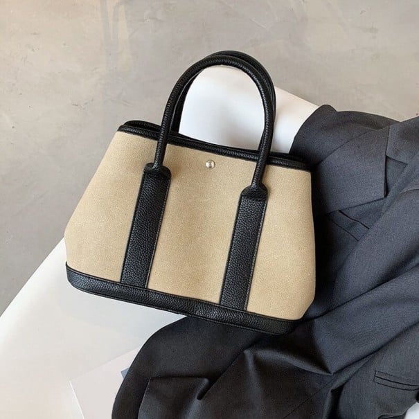 Dámská plátěná kabelka do ruky Pevný tvar Dvě krátká ucha Černé lemování Kovový cvoček na přední straně Rozměry 30 x 22 x 15 cm khaki