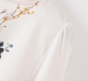 Damblus med blommönster Långa ärmar med knytning vid handlederna Rund halslinning Lätt och ledig passform Krämvit Bomull och polyester 4