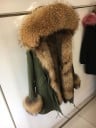 Dams vinterparka med huva kantad med päls från tvättbjörn Pälsfoder och manschetter Dragsko i midjan Längd till mitten av låret 9