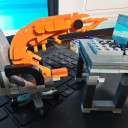 Conjunto de construção infantil em forma de camarão, que está sentado no escritório à mesa com um computador portátil numa cadeira de rodas, original 4