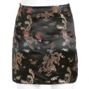Saia mini feminina com rasgo em estilo oriental. Tecido preto brilhante com padrão de dragões e fénixes. Botão em nó decorativo. Poliéster 3