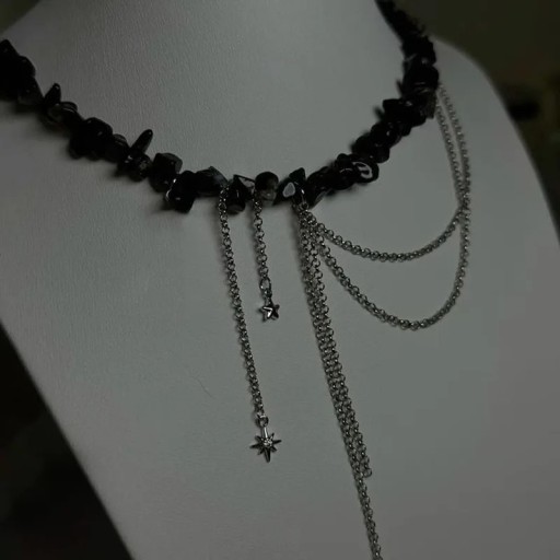 Černý náhrdelník z nepravidelných kamínků s visícími řetízky, hvězdou a drobným křížkem, výrazný asymetrický dekorativní šperk