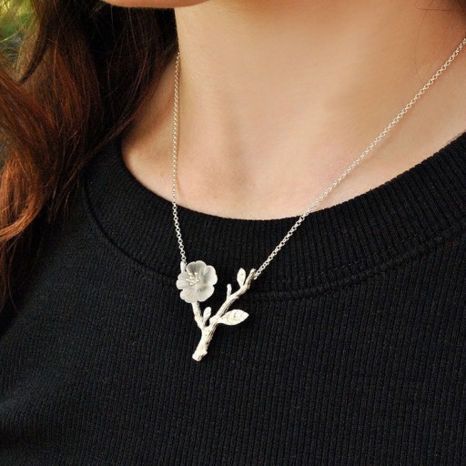 Damesketting met een bloem op een tak